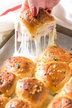 someone is dipping cheese on top of some rolls in the baking pan with other rolls