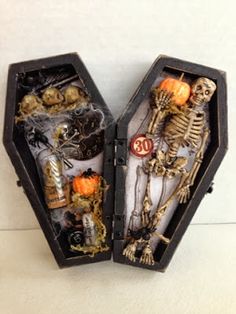 an open halloween box with skeleton decorations and skeletons in the inside, on a white surface