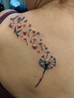 the back of a woman's shoulder with a dandelion tattoo