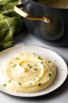 a white plate topped with mashed potatoes next to a pot