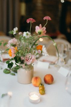 a vase filled with flowers sitting on top of a table next to fruit and candles