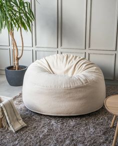 a large white bean bag chair sitting on top of a rug next to a potted plant