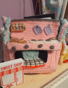 a pink crocheted oven sitting on top of a counter next to a sign