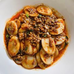 a white plate topped with sliced bananas covered in sauce and toppings on top of it