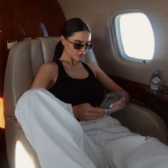 a woman sitting in an airplane looking at her cell phone