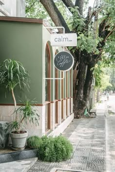 there is a sign that says calm on the side of a building next to a tree