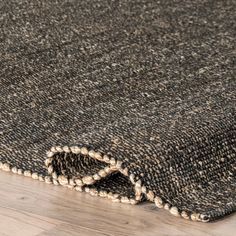 an area rug on the floor that has been made with dark colored wool and white beads