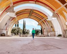 a woman is walking through an arch in the middle of a building with arches on both sides