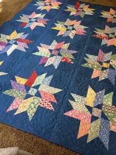 a blue quilt with stars on it sitting on the floor in front of a window