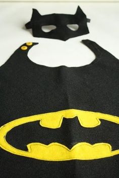 a black and yellow batman bib with a bat on it's chest, sitting on a white surface