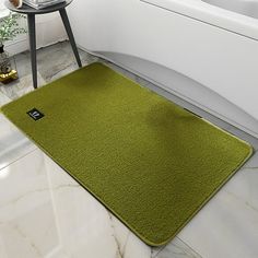 a bath room with a toilet and a green rug on the floor in front of a tub