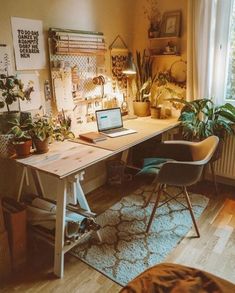 a desk with a laptop on top of it in a room filled with potted plants