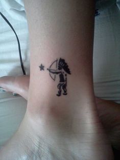 a small tattoo on the ankle of a person with an arrow and star in it