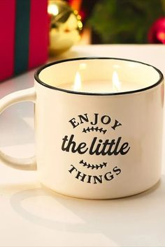 a white coffee mug sitting on top of a table next to a christmas ornament