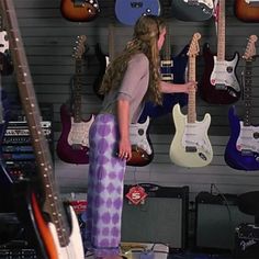 a woman is standing in front of guitars