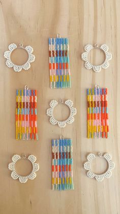 six pairs of beaded earrings and bracelets on a wooden surface with beads attached to them