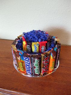 a cup filled with candy bars on top of a wooden table next to a wall