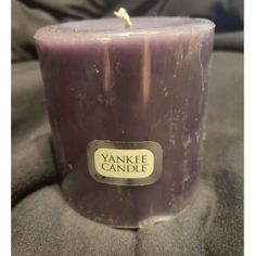 a purple candle sitting on top of a black cloth covered bedding with a label reading yankee candle