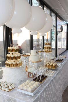 a table topped with lots of cupcakes and cake covered in white frosting