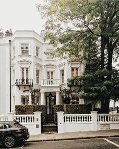 a black car parked in front of a white building with balconies on the windows