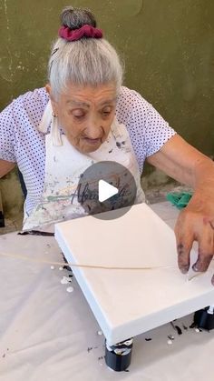 an older woman is working on a piece of art