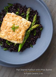 a blue plate topped with rice and asparagus on top of a wooden table