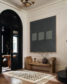 a black and white area rug in front of a doorway with a painting on the wall