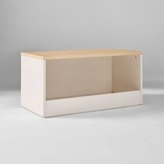 an empty white box sitting on top of a wooden table next to a gray wall