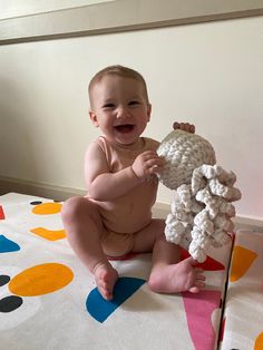 a baby sitting on the floor holding a stuffed animal