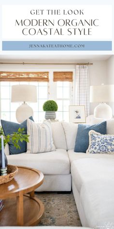 a living room with white couches and blue pillows on the sofa, in front of a