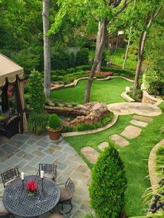 an outdoor patio with tables and chairs in the center, surrounded by lush green trees