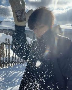 a person standing outside in the snow with their hands up and sun shining through them