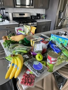 the kitchen counter is full of food and drinks, including bananas, apples, watermelon, raspberries, kiwis