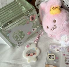 a pink teddy bear sitting on top of a bed next to a box with stickers