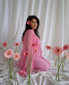 a woman sitting on the ground with pink flowers in front of her and behind her