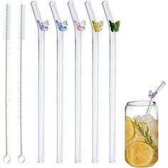 four glass straws with butterflies on them next to a cup filled with lemonade