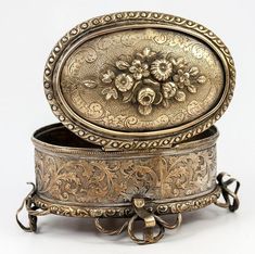 an ornate metal box with flowers on the lid is shown in front of a white background