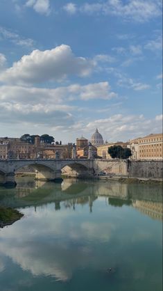 a bridge over a body of water with buildings in the background and clouds in the sky