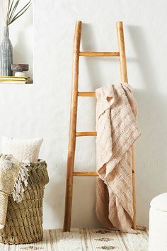 a ladder leaning up against a wall next to a basket with a towel on it