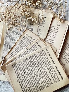 several old books are laying on top of each other with flowers growing out of them