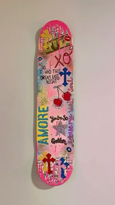 a skateboard covered in stickers and writing on it's bottom half is laying against a white wall