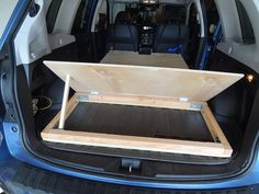 an open trunk in the back of a blue minivan with its door open and seat up