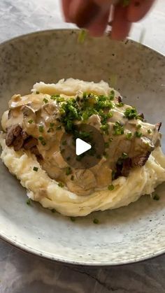 a plate with mashed potatoes topped with mushrooms and parsley on top, being held by a person