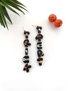 two pairs of black and orange beaded earrings on top of a white surface next to a plant