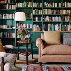 a living room filled with furniture and lots of bookshelves covered in green bookcases