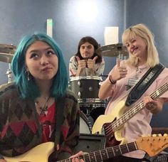 two women with blue hair playing guitars in a recording studio while another woman looks on