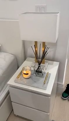 a bedroom with a bed, nightstand and candles on the night stand in front of it