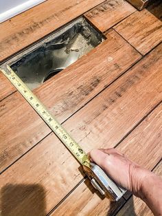 a person measuring the width of a wooden floor