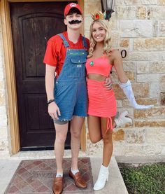 a man and woman in overalls pose for a photo outside their house with fake moustaches on