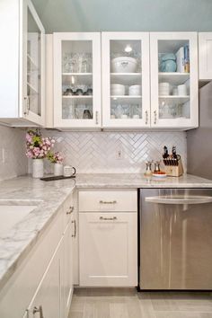 a kitchen with white cabinets and stainless steel dishwasher